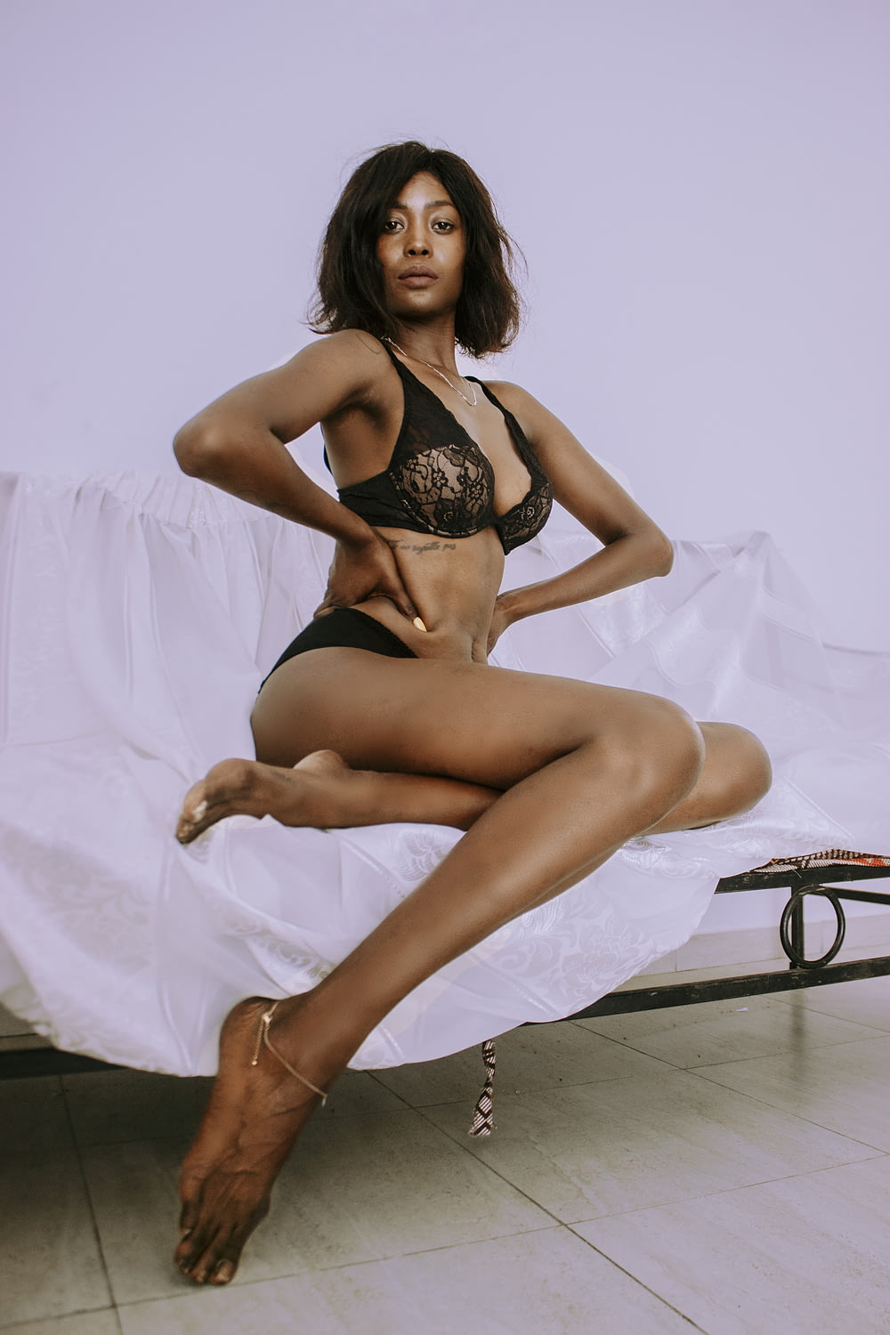 a woman in a black lingerie sitting on a bed