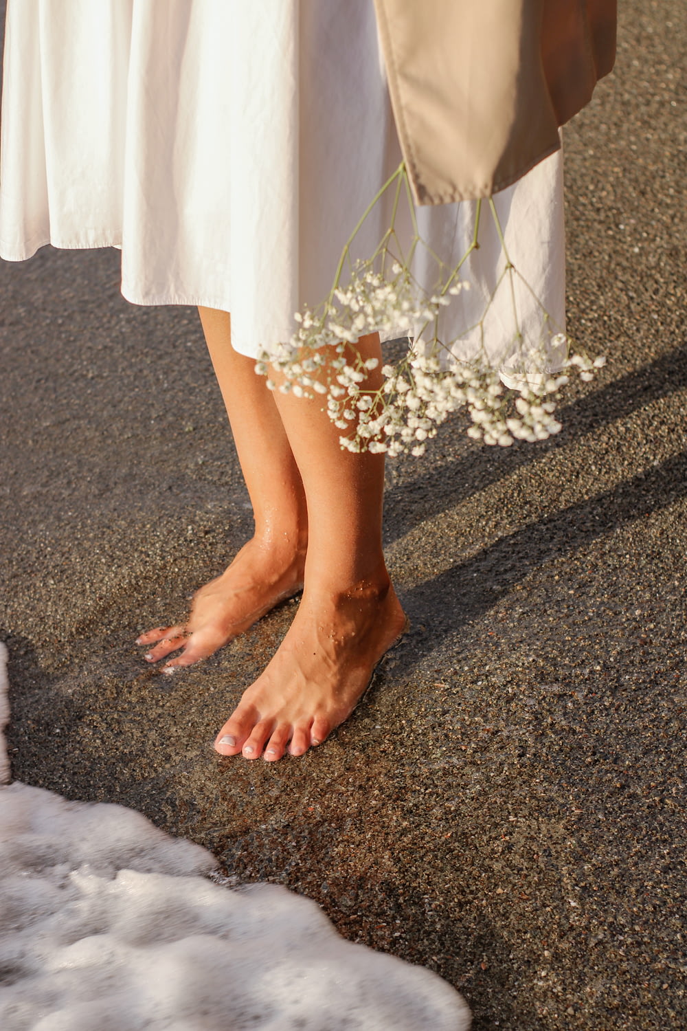 Eine Frau in einem weißen Kleid steht neben einer weißen Blume