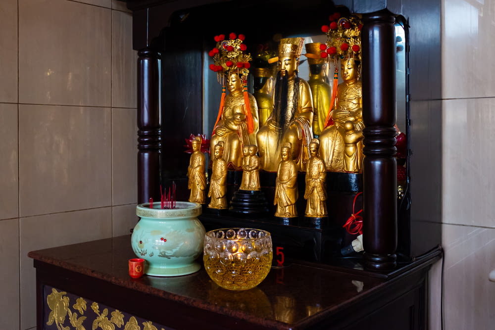 a small shrine with gold statues and a glass bowl