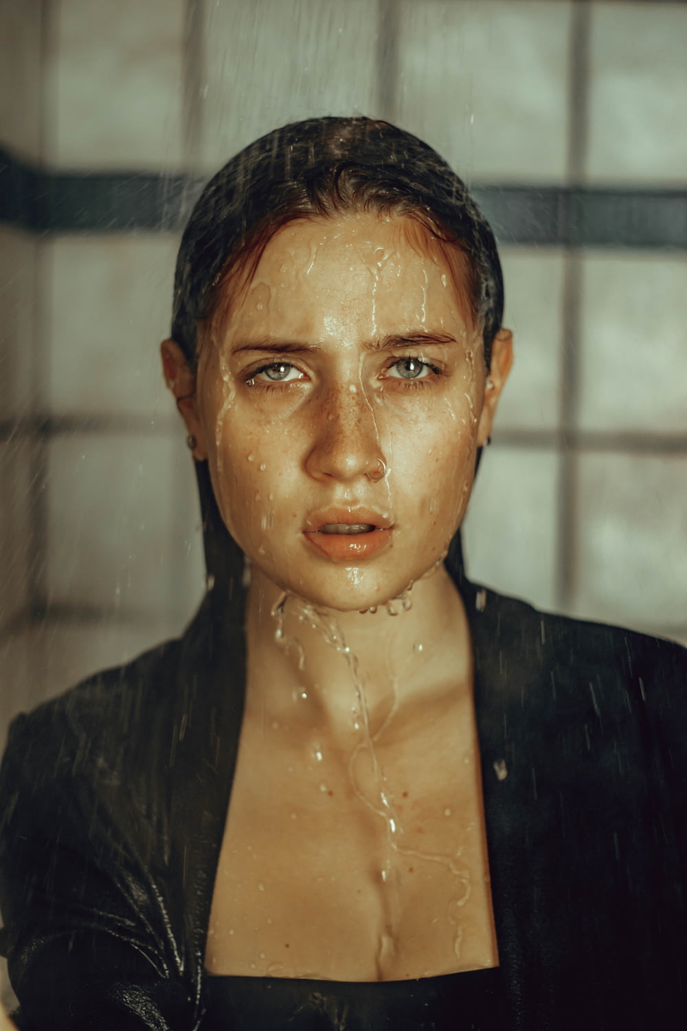 a woman with a wet face is standing in the shower