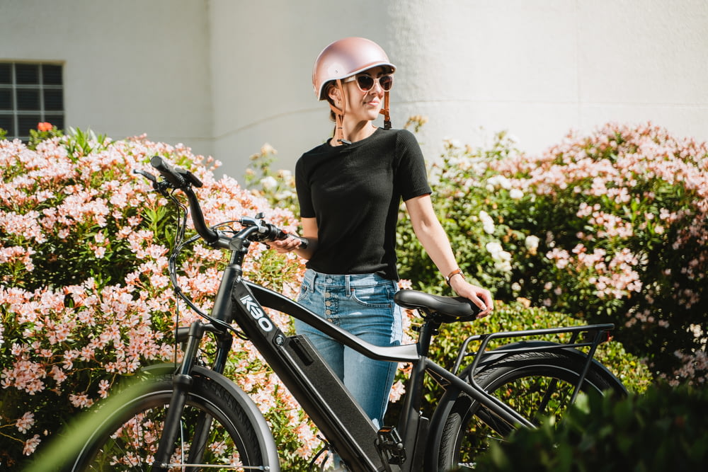 a woman wearing a helmet standing next to a bike