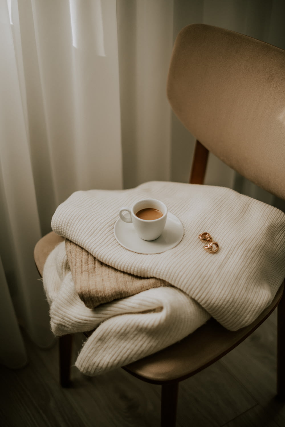 a cup of coffee sits on a blanket on a chair