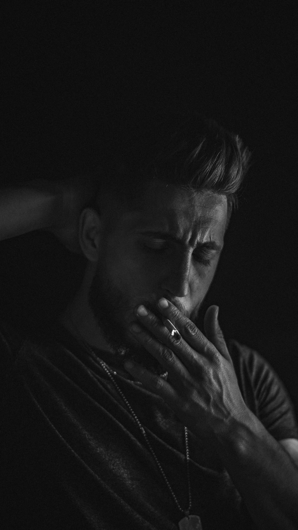 a man in a dark room holding his hands to his face