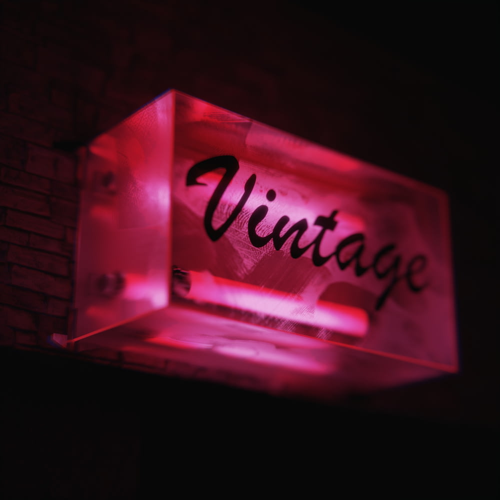 Un letrero iluminado que dice vintage en una pared de ladrillo