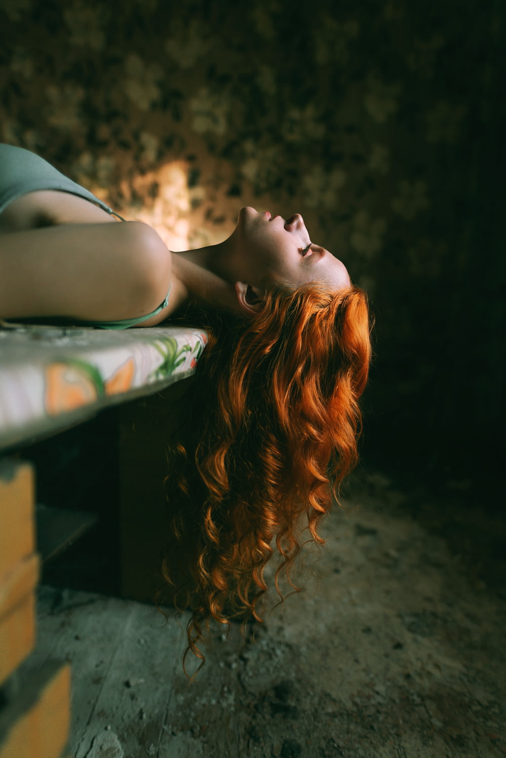a woman with red hair laying on a bench