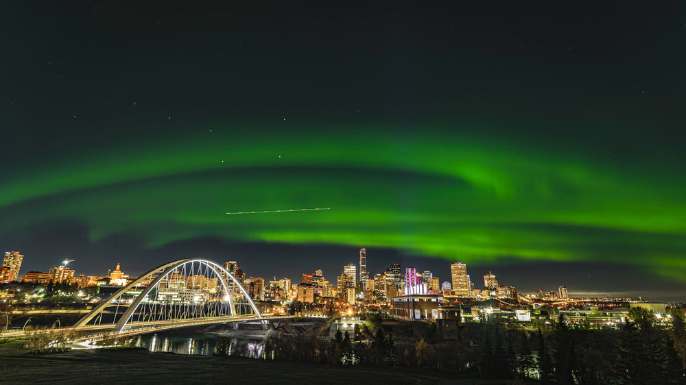 a green aurora bore over a city at night