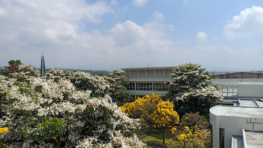 a building surrounded by trees and flowers on a cloudy day