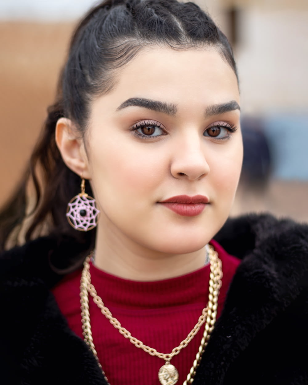 a woman wearing a red sweater and gold necklace