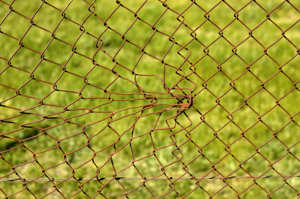 a close up of a fence with grass in the background