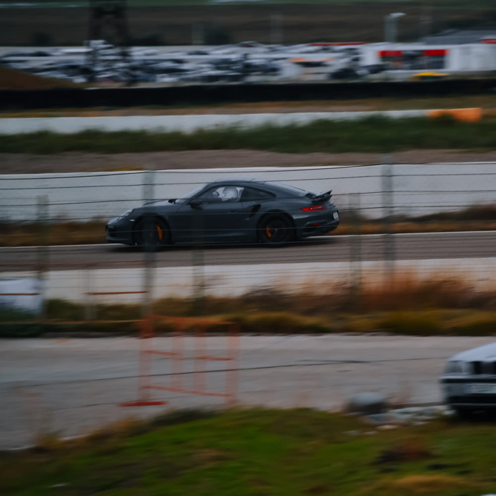 a black car driving down a race track
