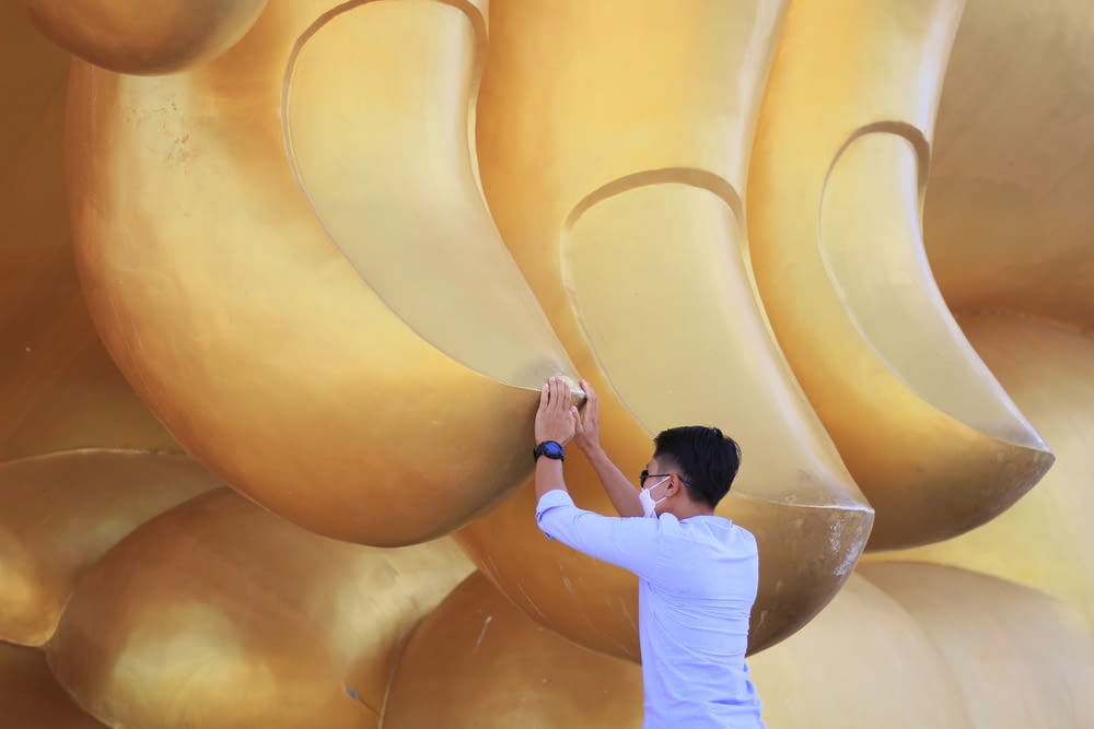 a man standing next to a giant golden statue