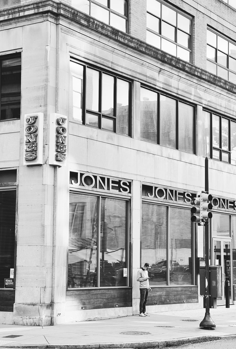 a black and white photo of a man standing in front of a jones jones store
