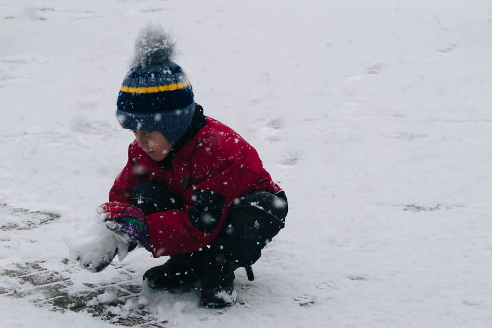 a young boy playing in the snow with a frisbee