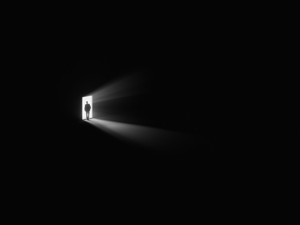 una persona in piedi in una porta con una luce che la attraversa