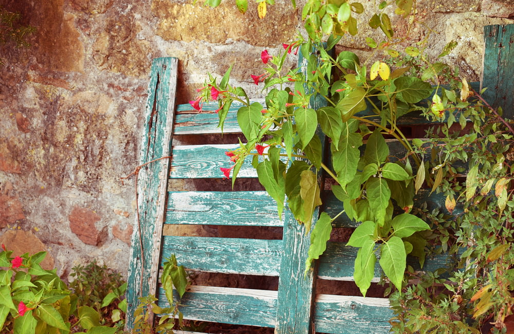 a green wooden bench sitting next to a brick wall