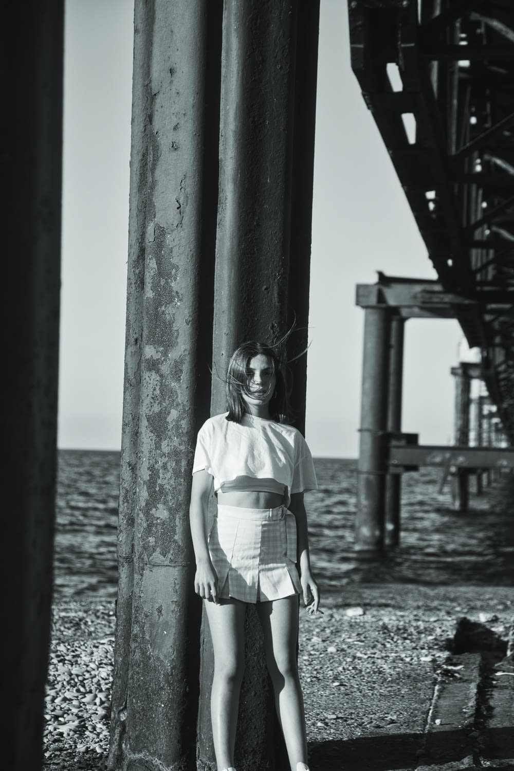 a woman standing next to a pole near the ocean