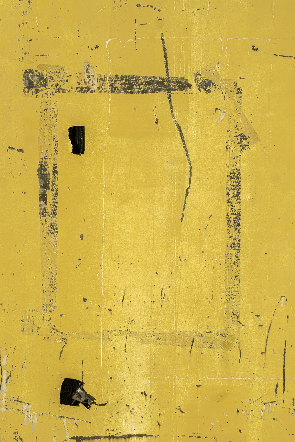 a piece of yellow and black paint on a wall