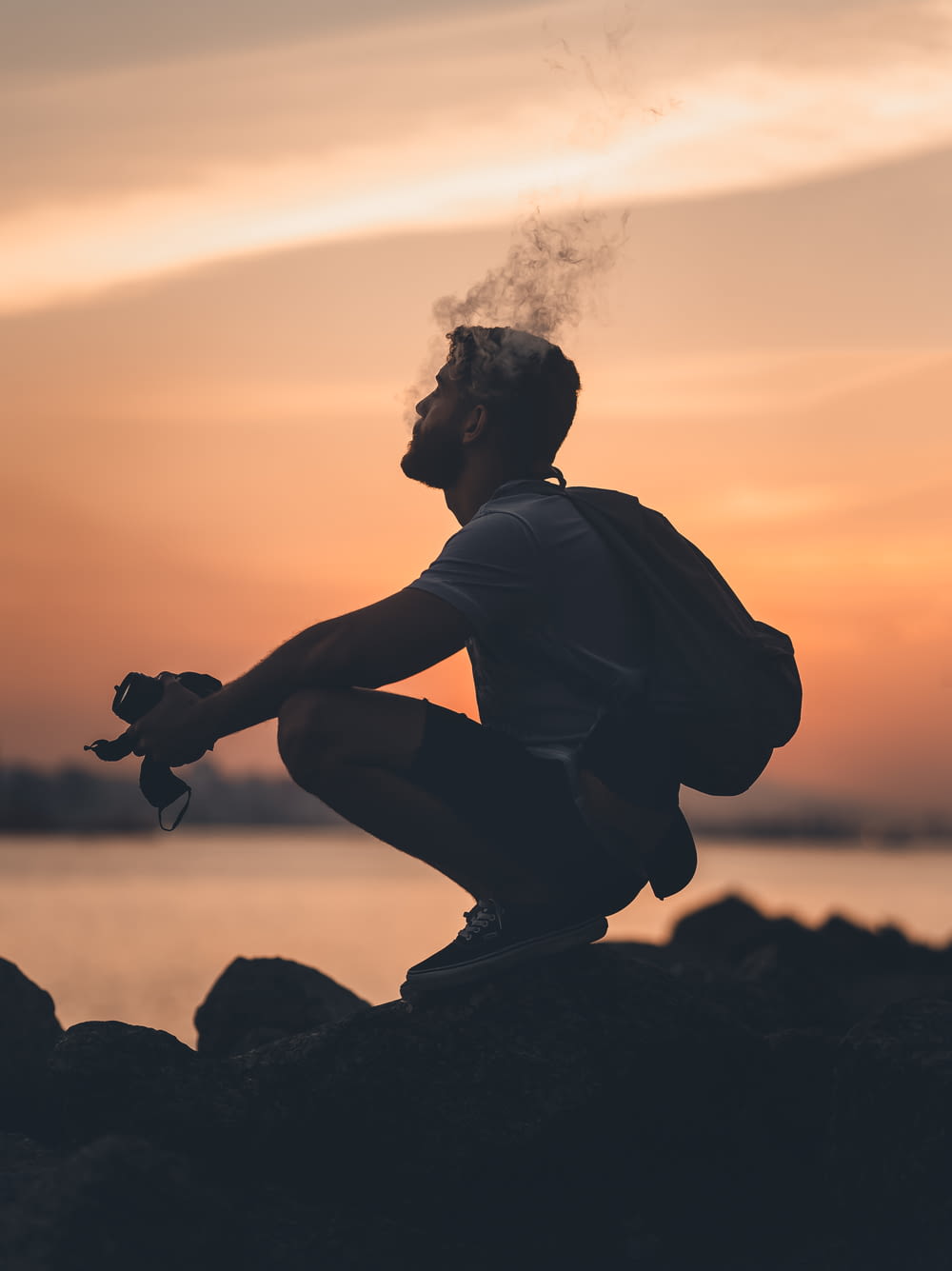 a man sitting on a rock smoking a cigarette