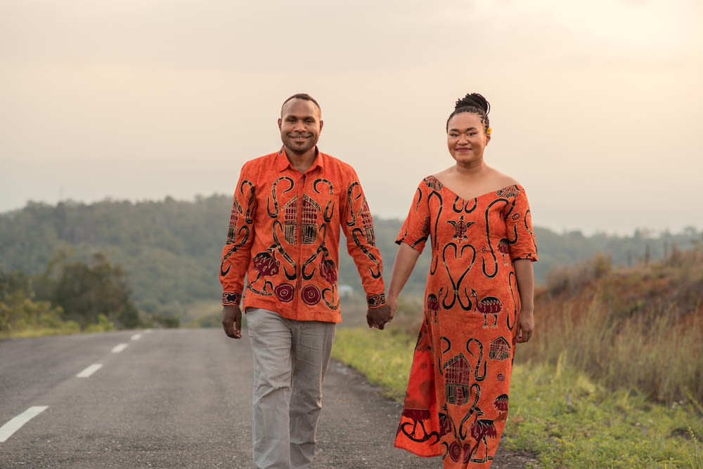 a man and woman walking down a road holding hands