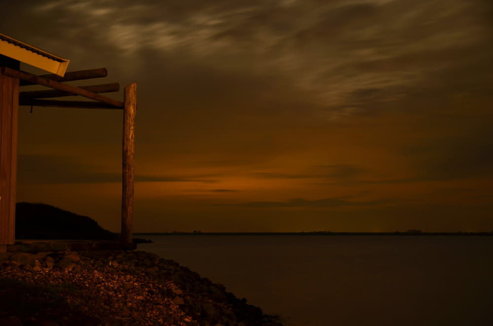 a wooden structure sitting on top of a beach next to a body of water