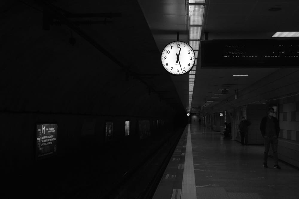a black and white photo of a clock at a train station