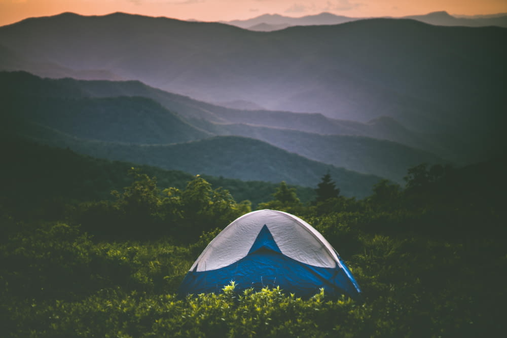 a tent in the middle of a field with mountains in the background