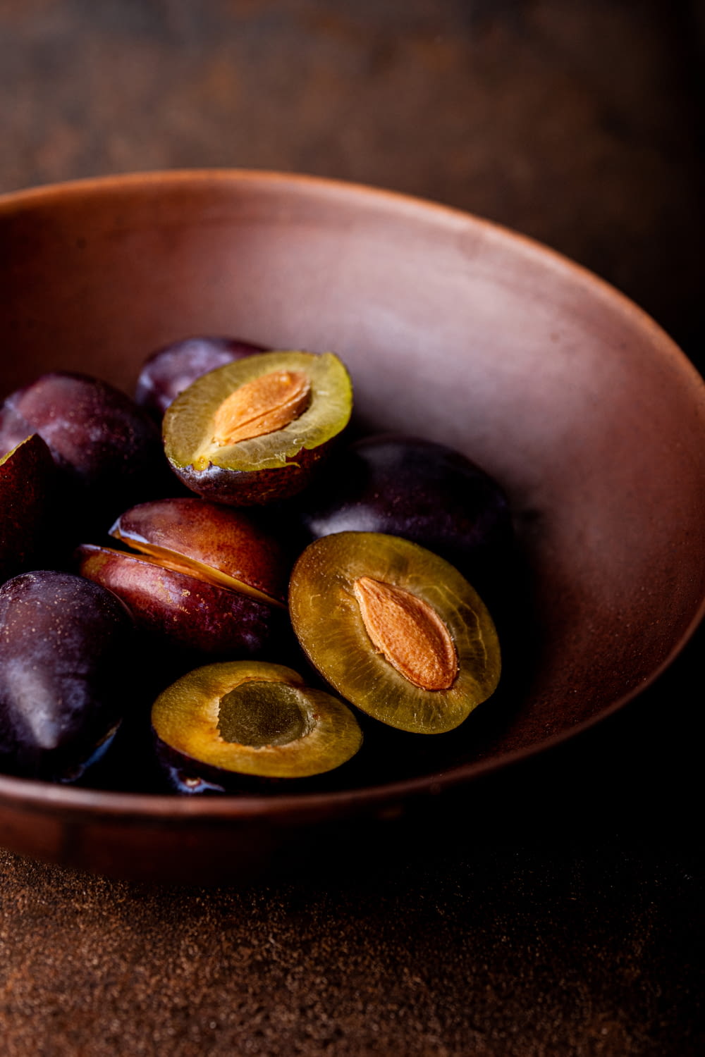 a bowl filled with plums on top of a table