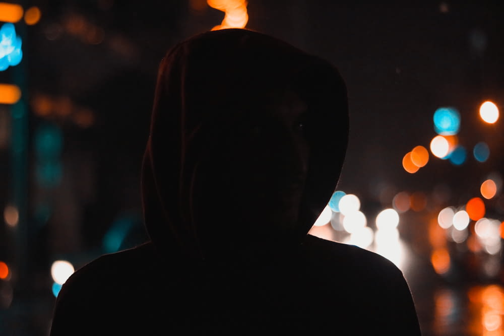 a person in a hoodie standing in the dark