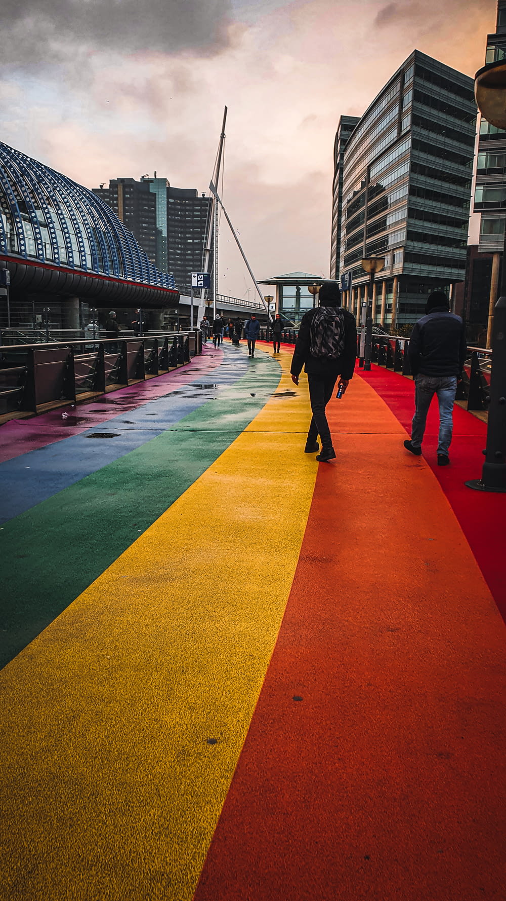 a rainbow colored walkway with people walking on it