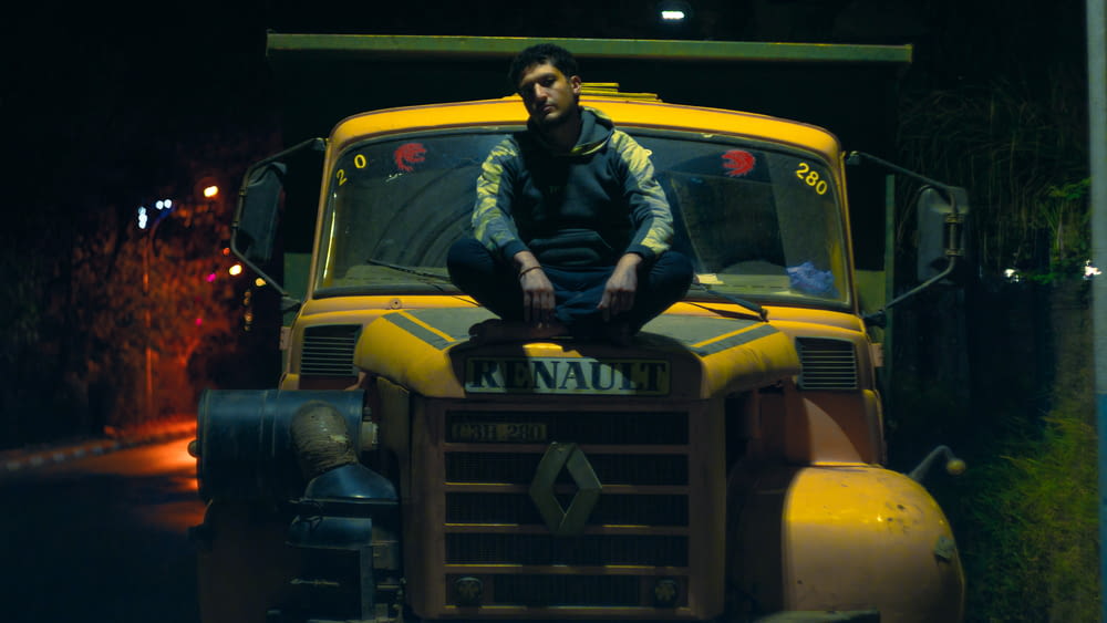 a man sitting on top of a yellow truck