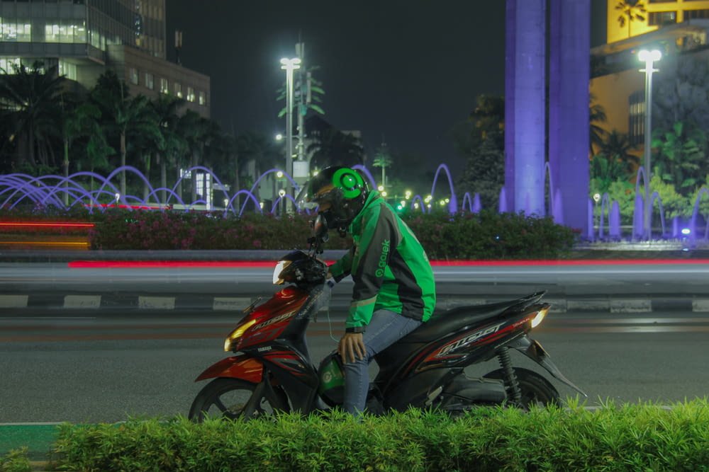 a man wearing a green mask riding a red scooter