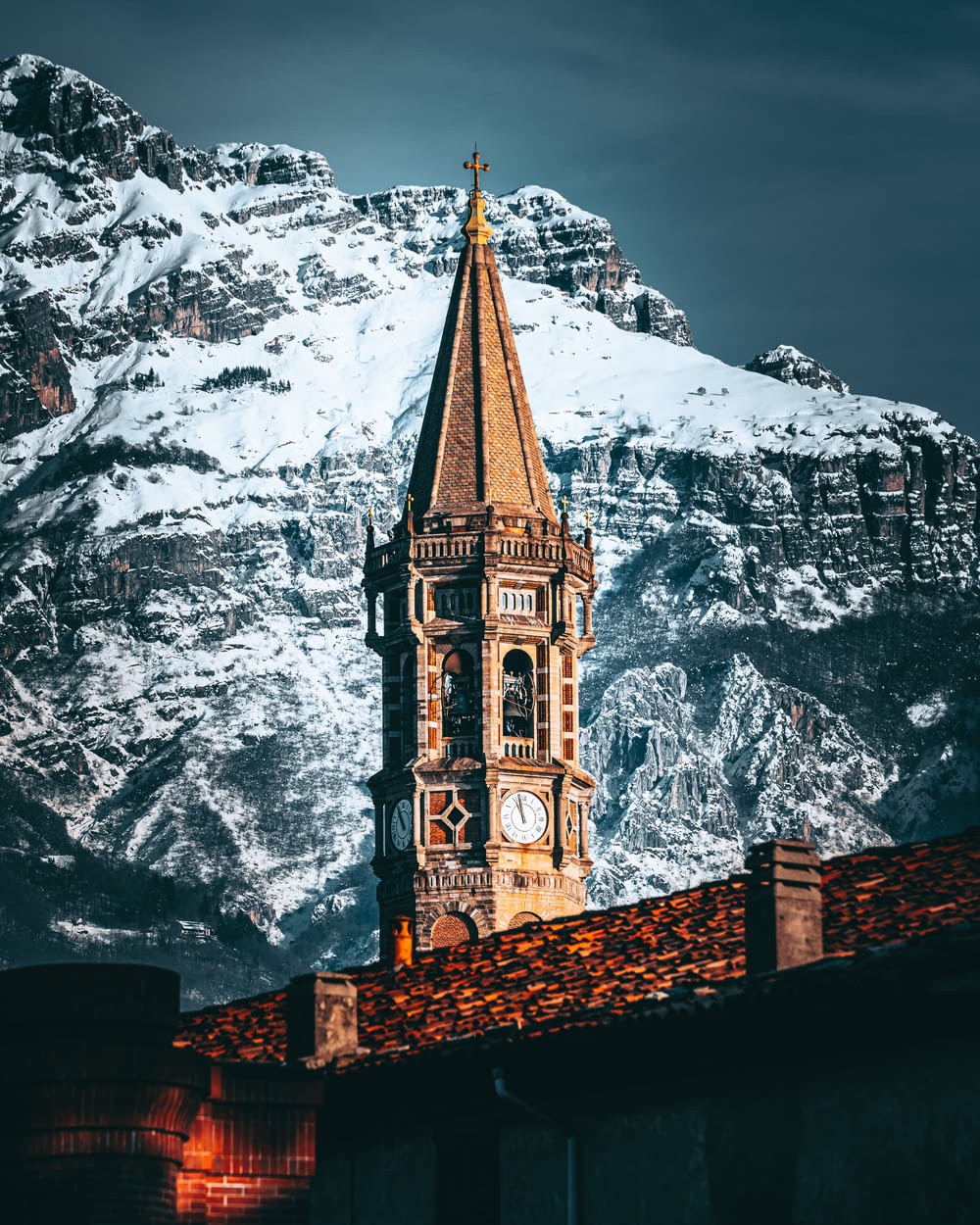 une tour de l’horloge au sommet d’un bâtiment avec une montagne en arrière-plan