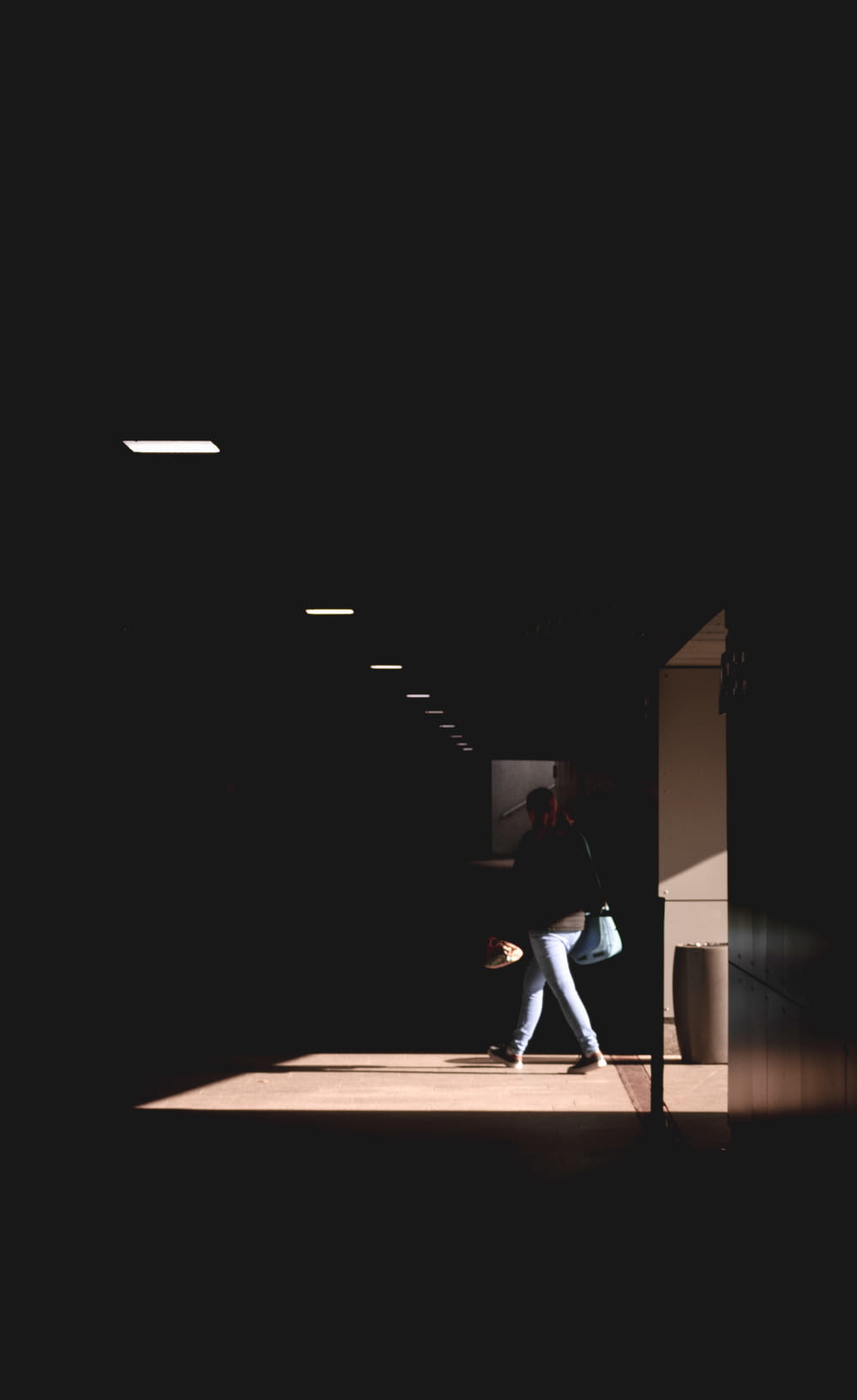 a woman is walking down a dark hallway