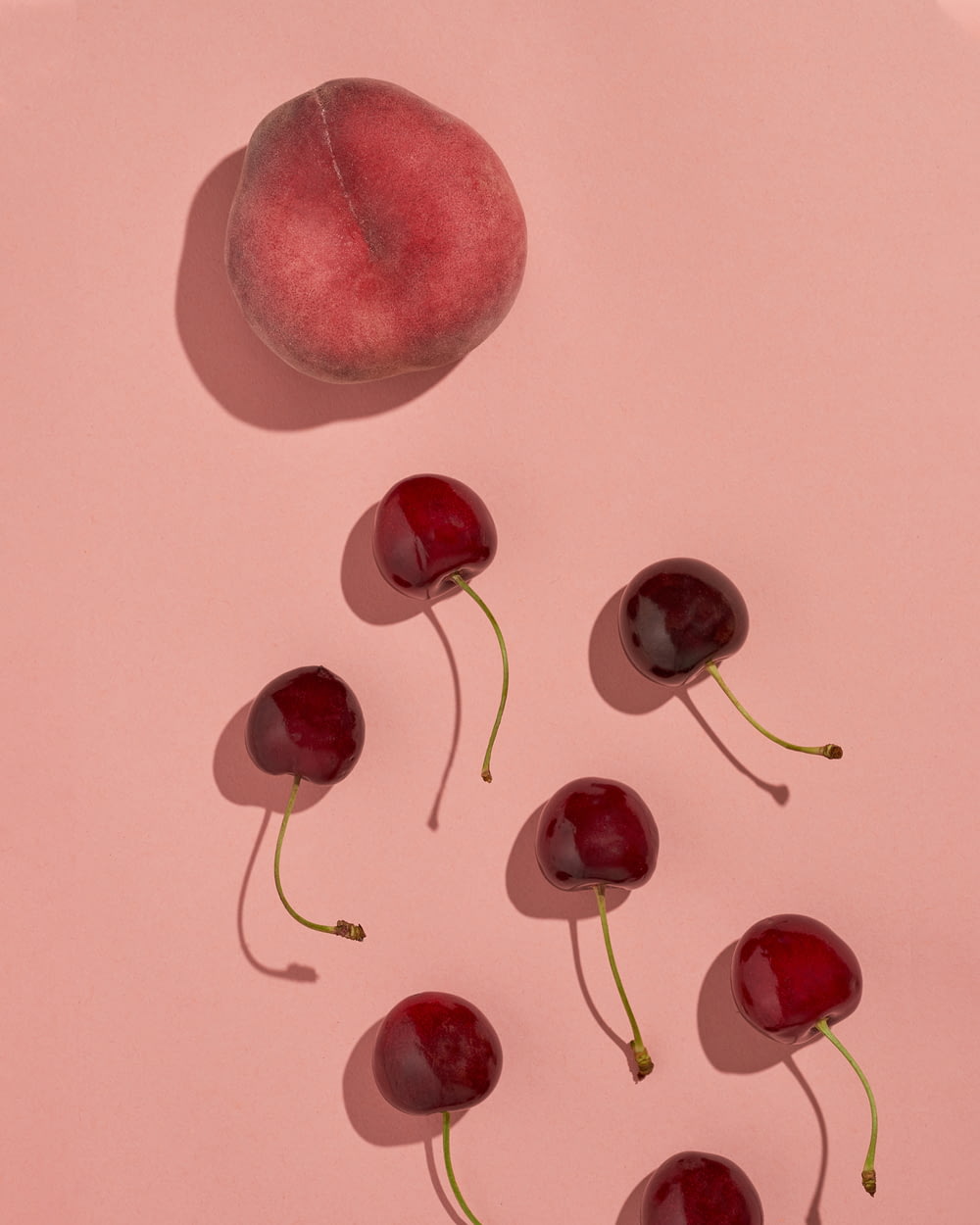 a group of cherries sitting on top of a pink surface