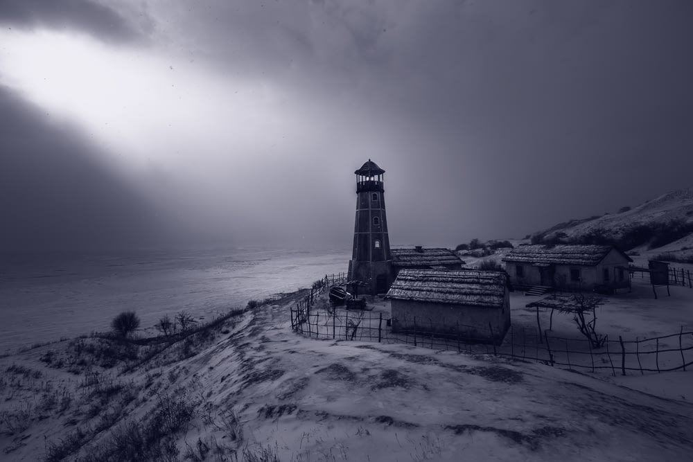 a black and white photo of a lighthouse in the snow
