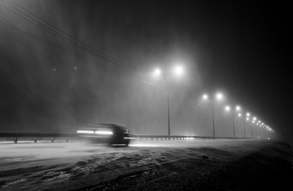 a truck driving down a snow covered road at night