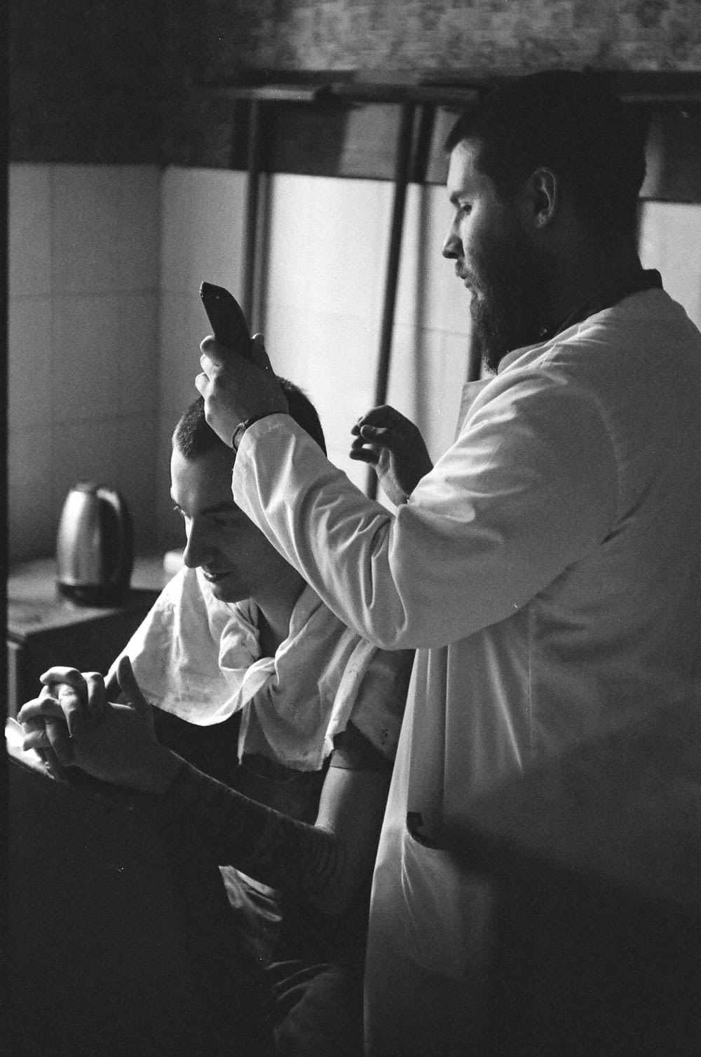 a black and white photo of a man brushing his hair
