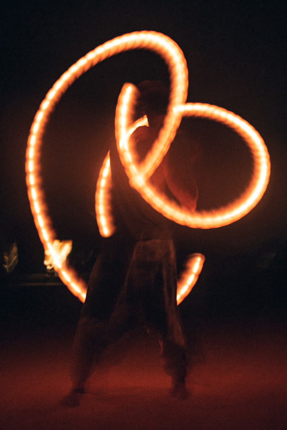 a man is spinning a fire ring around in the dark
