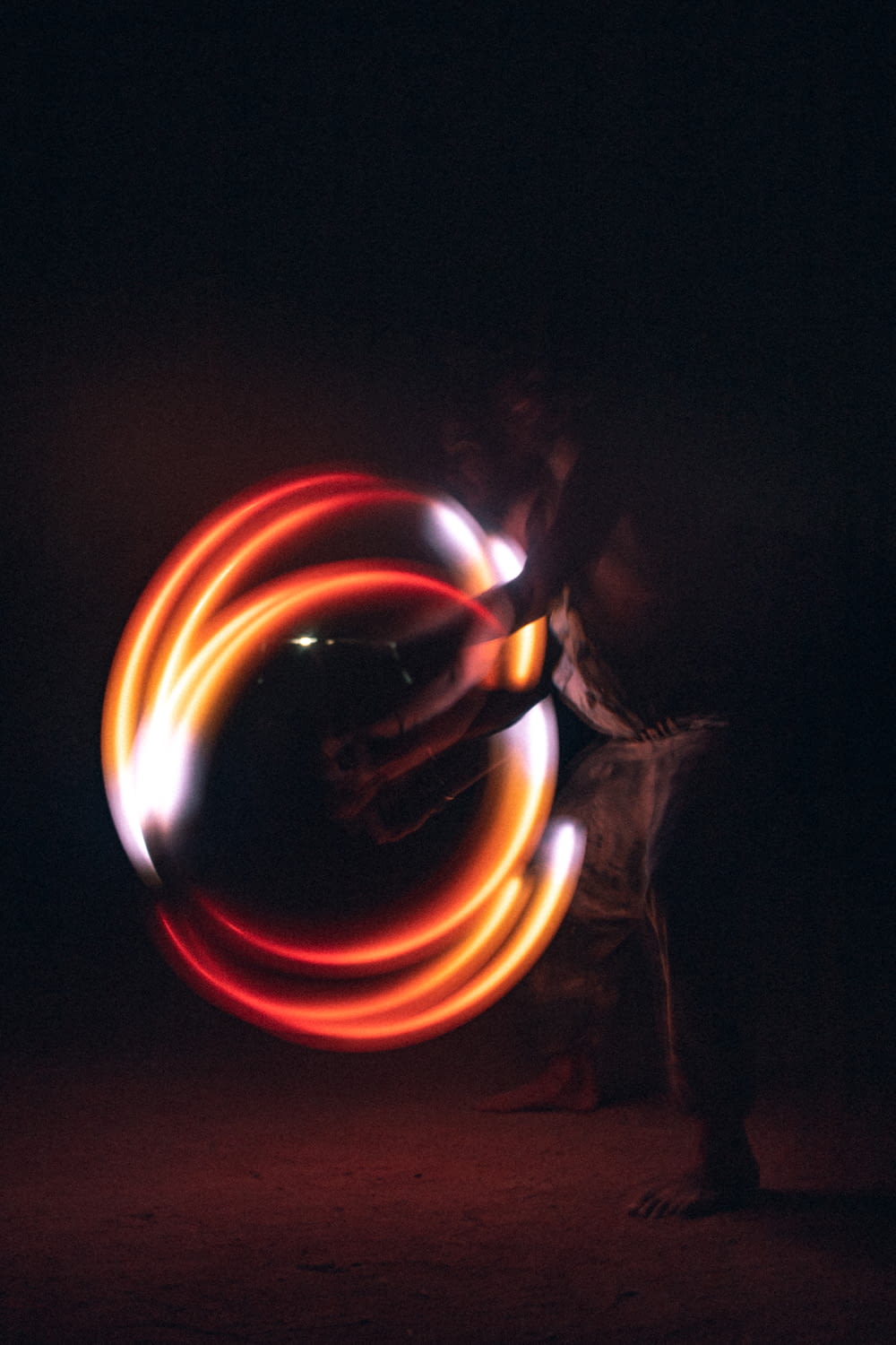 a man is spinning a circular light in the dark
