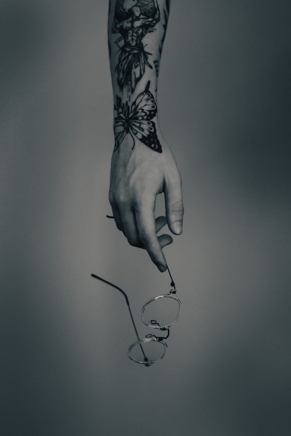 a hand holding a pair of glasses with a tattoo on it