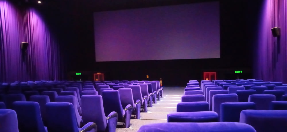 a theater with rows of seats and a projector screen