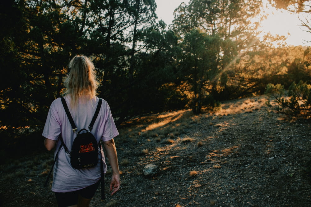 a woman with a backpack walking up a hill
