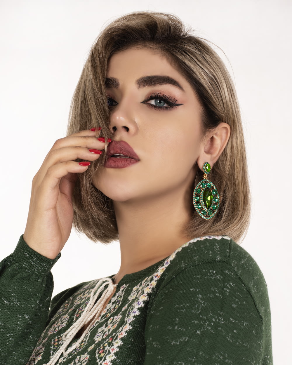 a woman with a green sweater and earrings