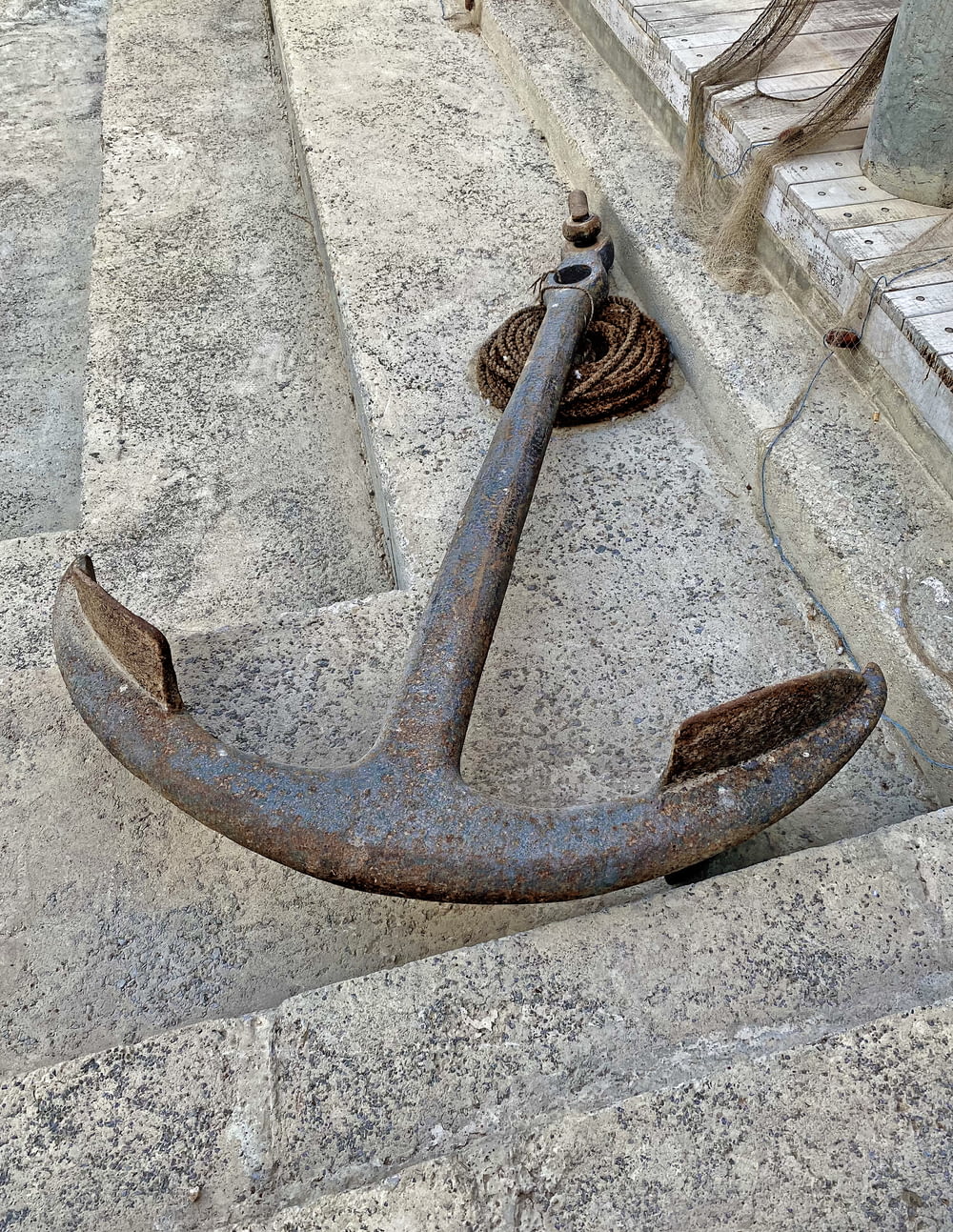 an anchor laying on the ground next to a rope