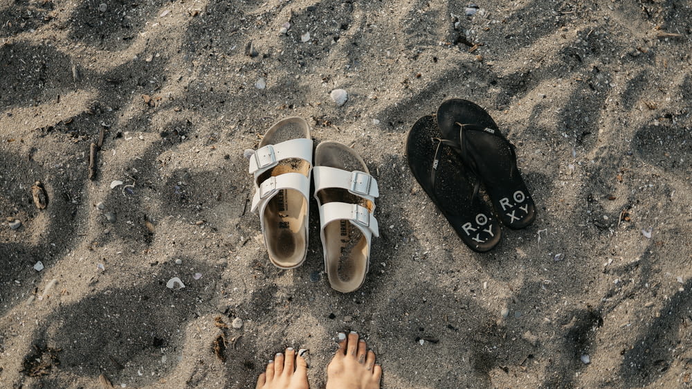 Un par de sandalias sentadas en la parte superior de una playa de arena