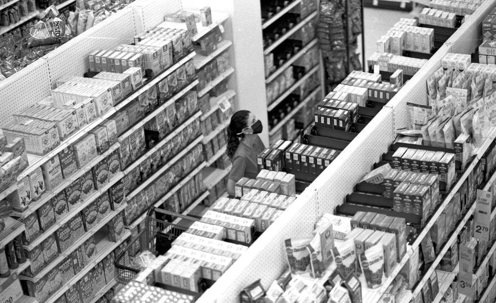 a black and white photo of a woman shopping in a grocery store