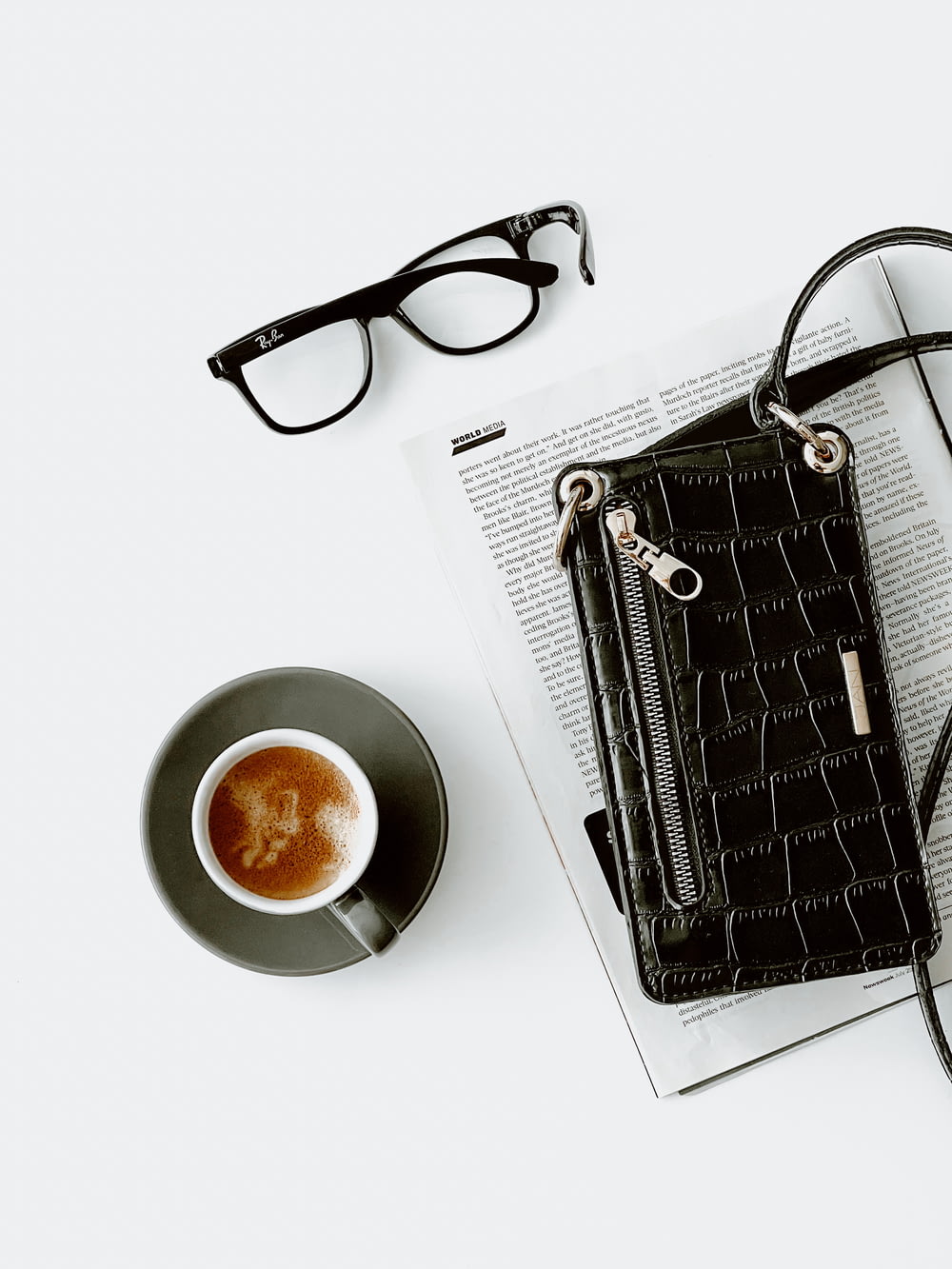 a black purse sitting on top of a book next to a cup of coffee