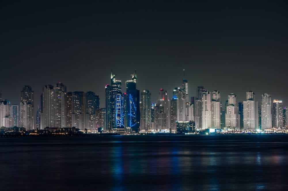 a city skyline at night with lights reflecting off the water