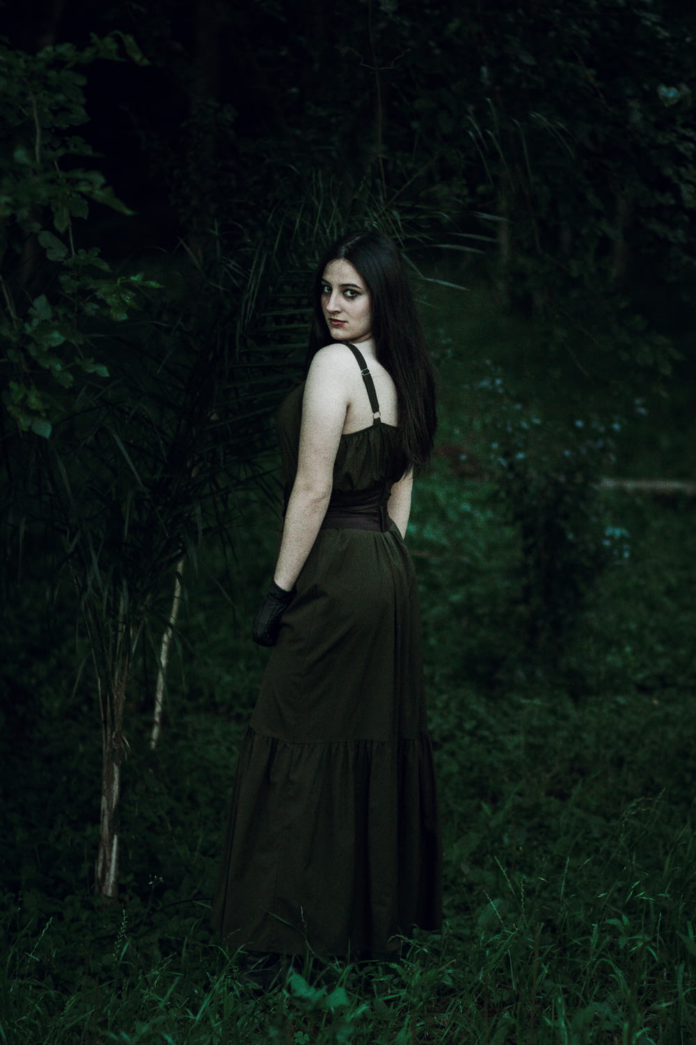 a woman in a black dress standing in a forest
