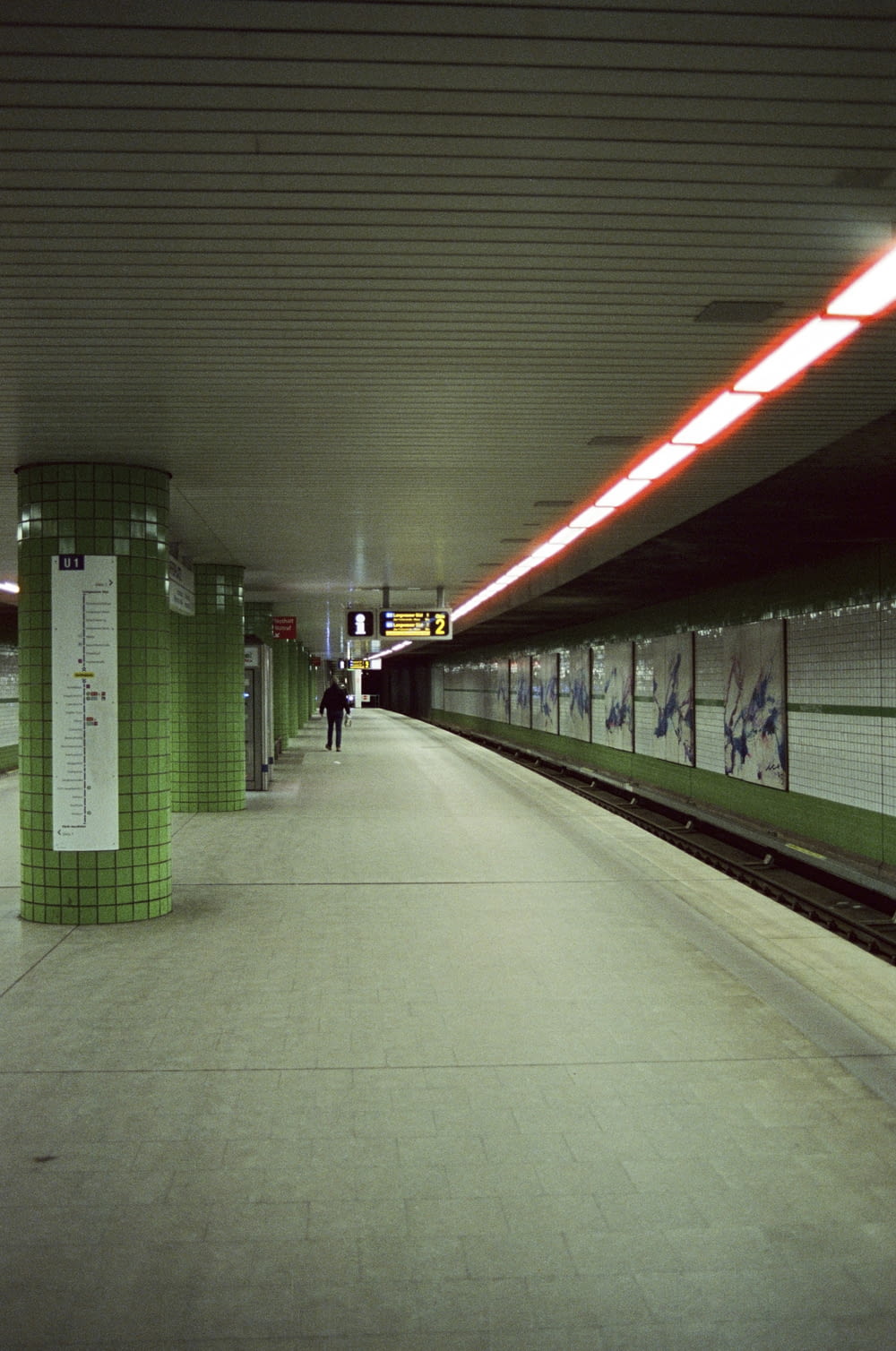 a subway station with a person walking on the platform